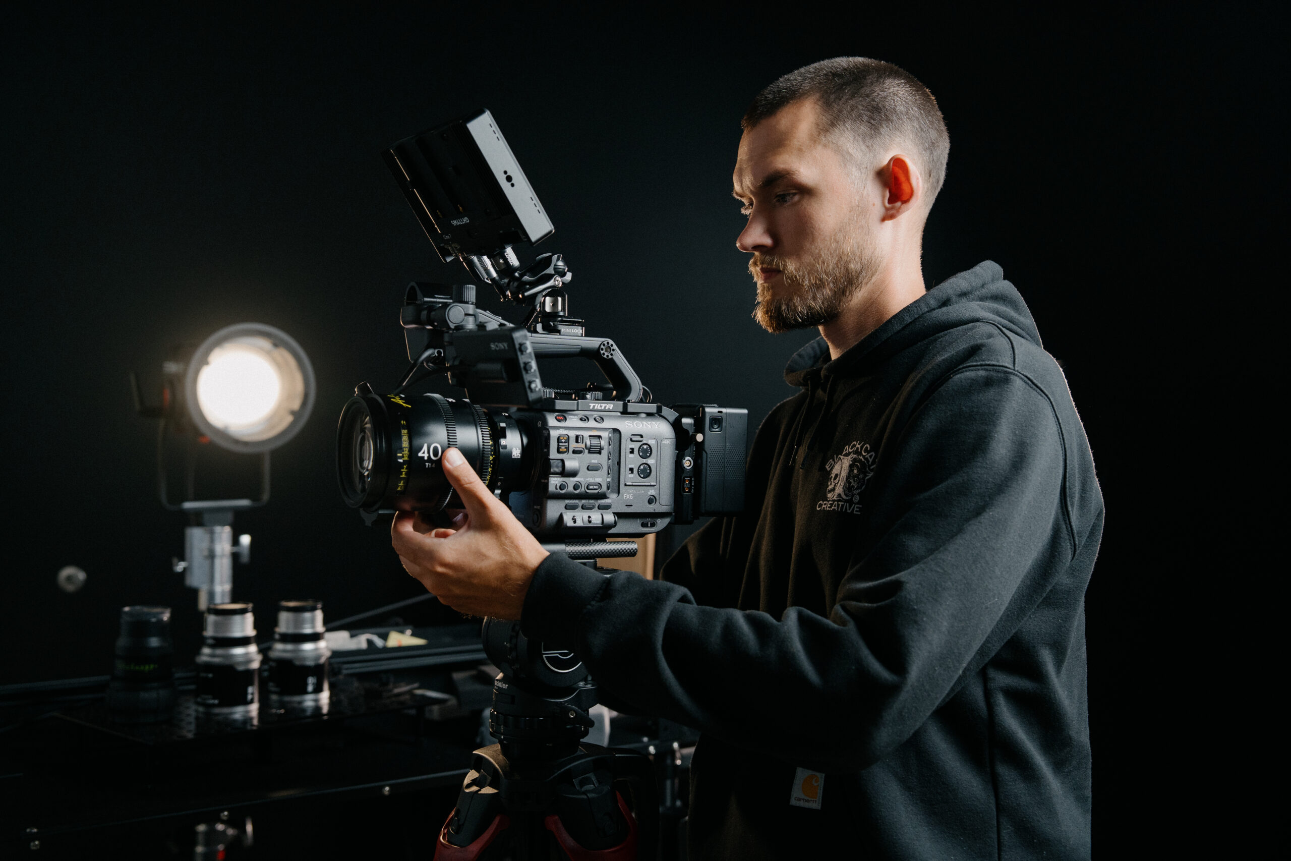 Keagan Henman adjusting camera in studio with lighting equipment.