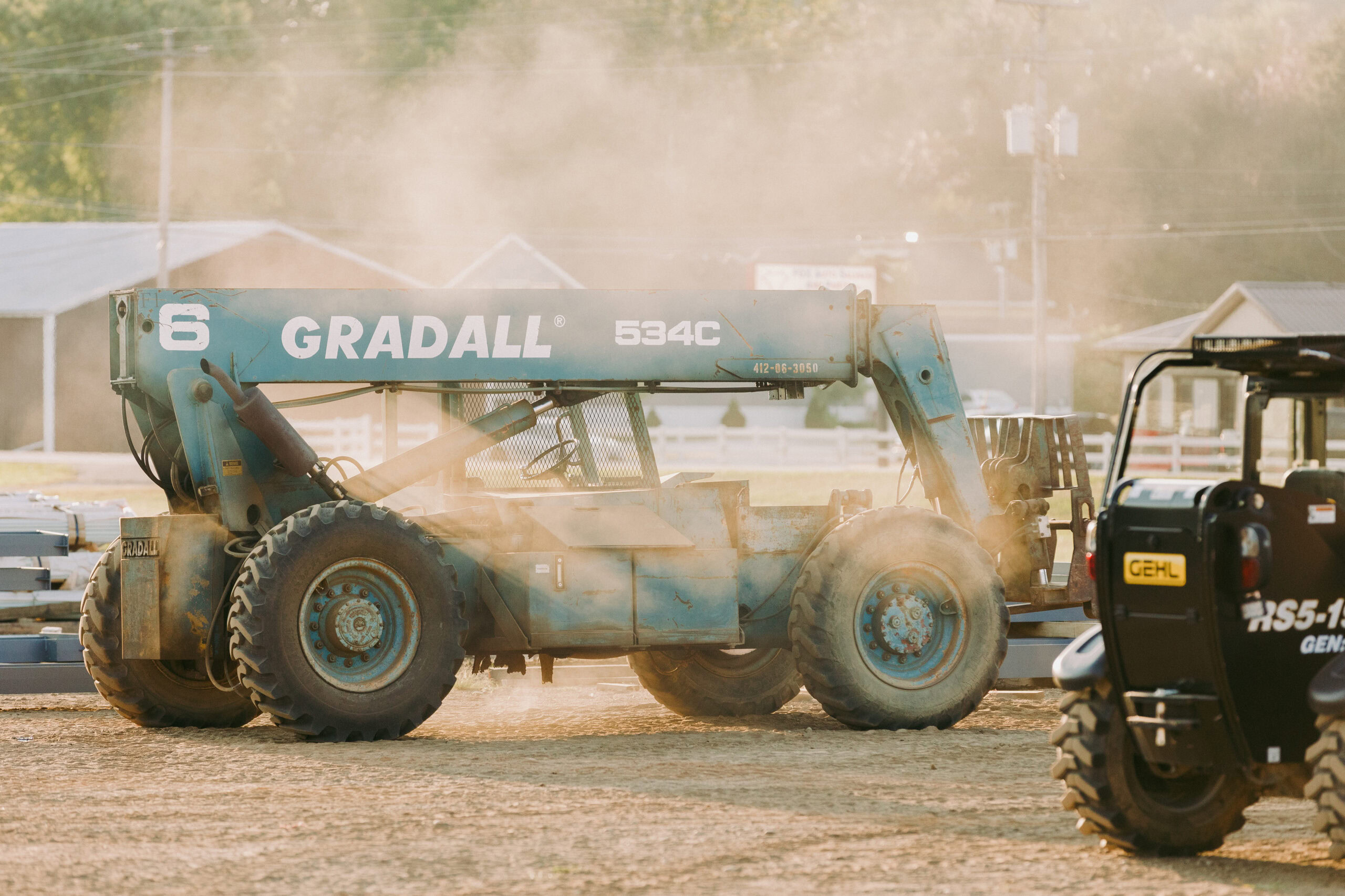 458A6102-scaled Heavy construction equipment at a construction site with dust in the air.