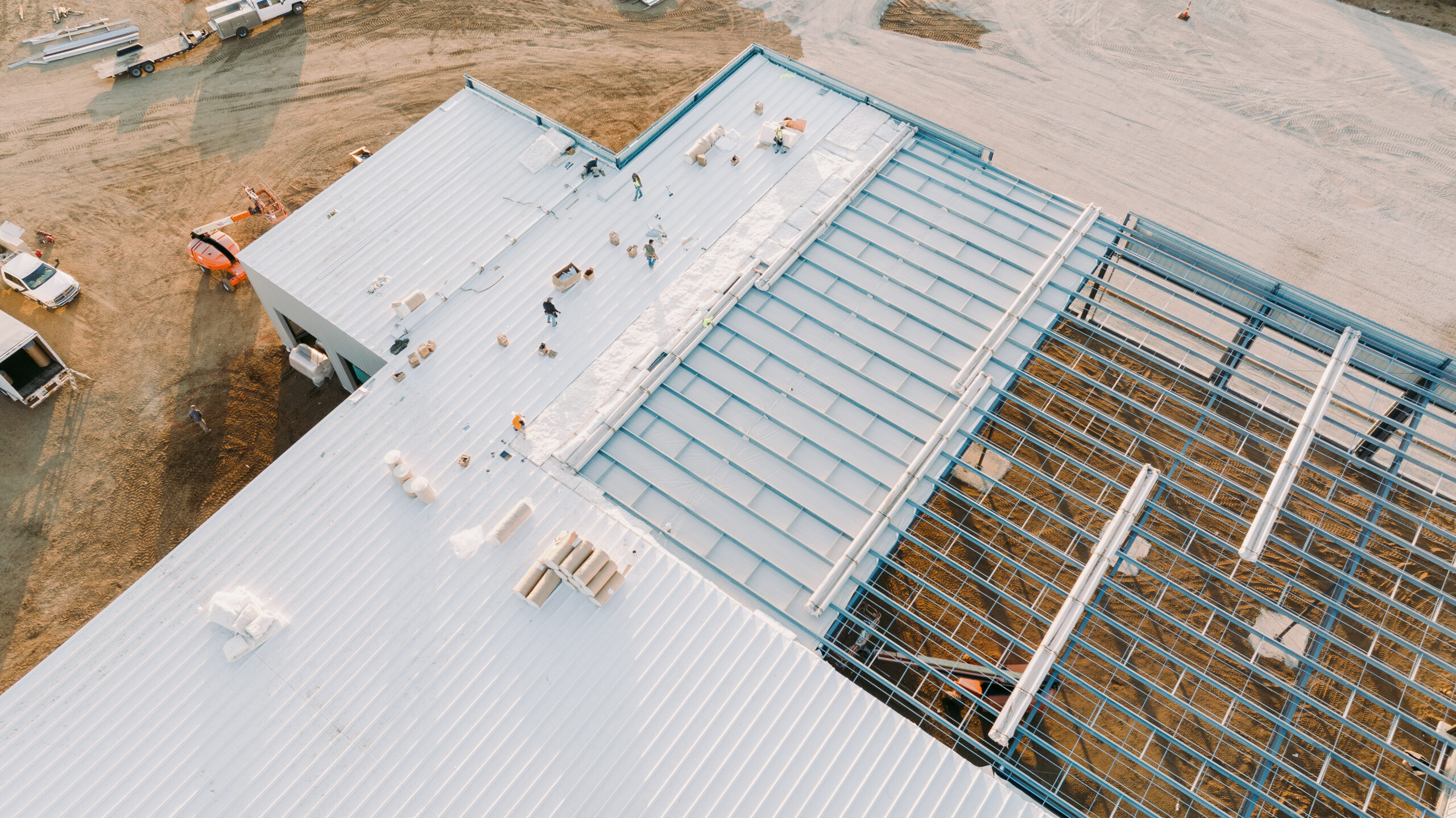 Aerial view of a construction site with a partially built metal roof structure.