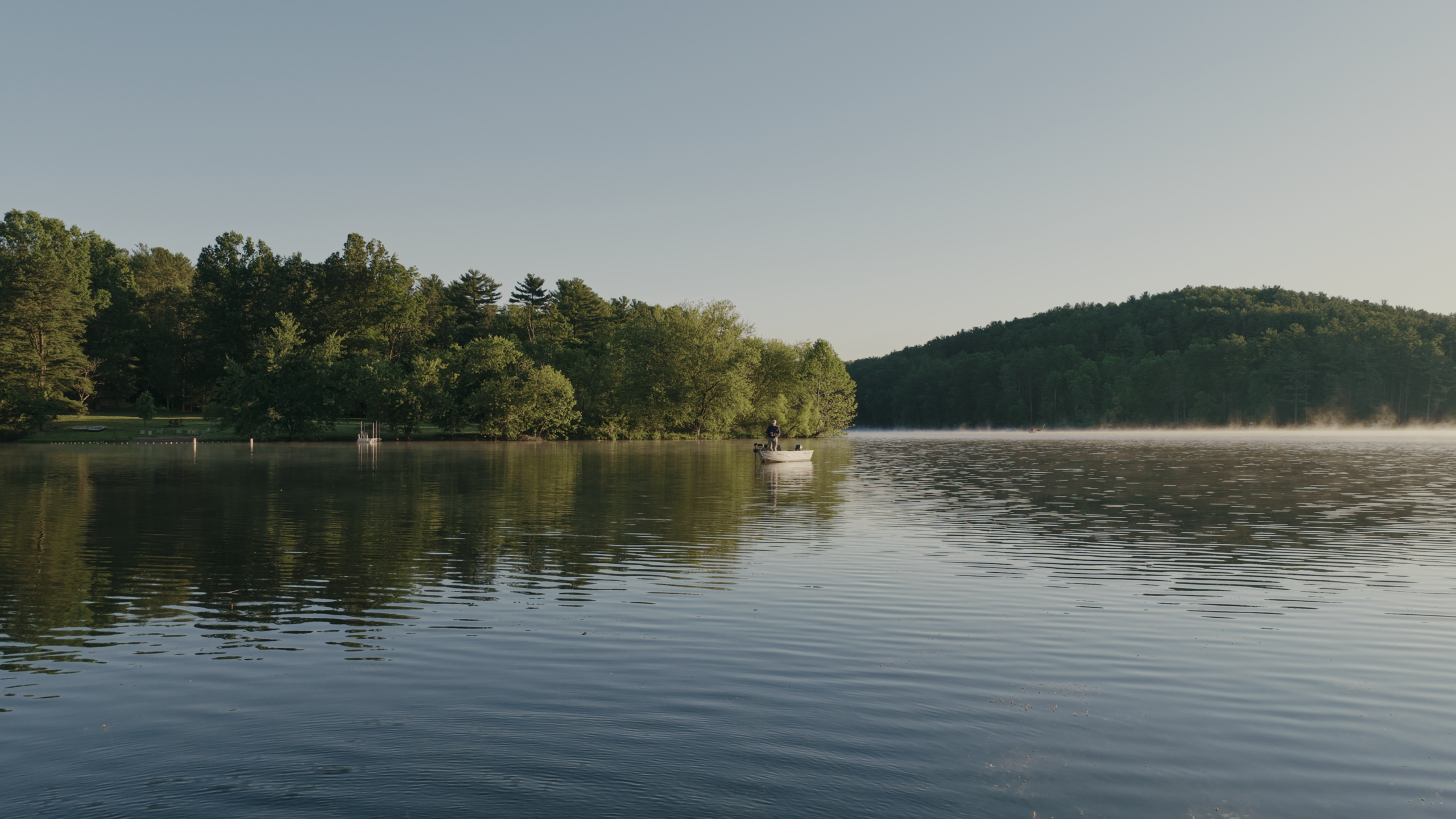 Screenshot 2026-09-24 at 5.04.31 PM Serene lake scene with trees and hills in the background at sunset.